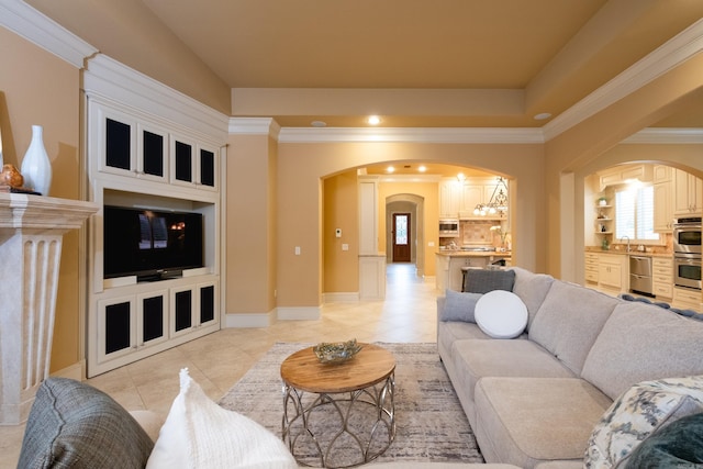 living area with light tile patterned floors, arched walkways, baseboards, a tray ceiling, and crown molding