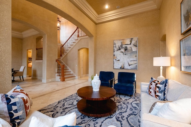 living room featuring ornamental molding, arched walkways, a towering ceiling, and stairs