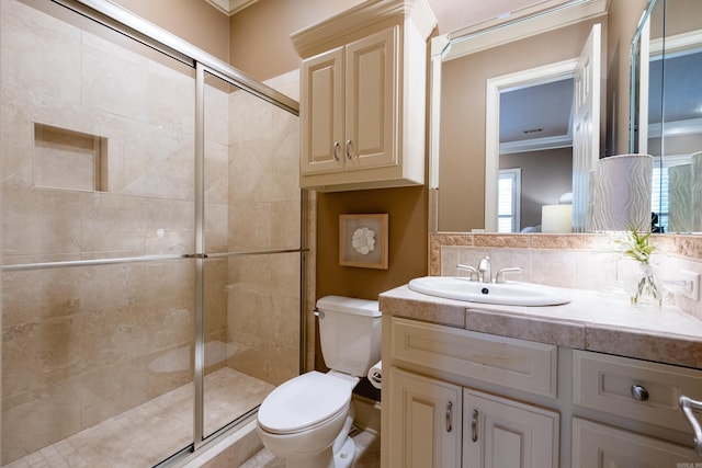 bathroom with toilet, vanity, backsplash, a shower stall, and crown molding