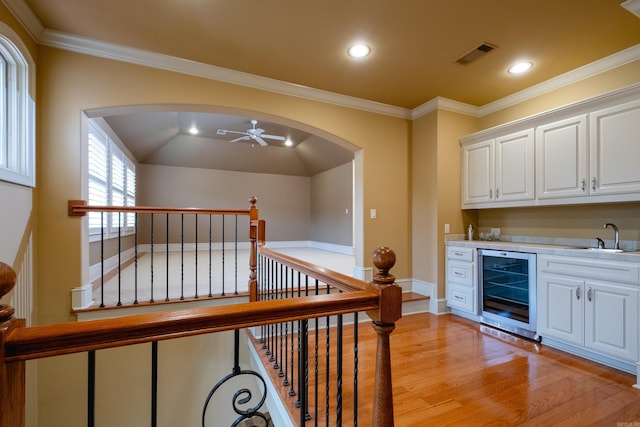 interior space featuring wine cooler, visible vents, a sink, ceiling fan, and light wood-type flooring