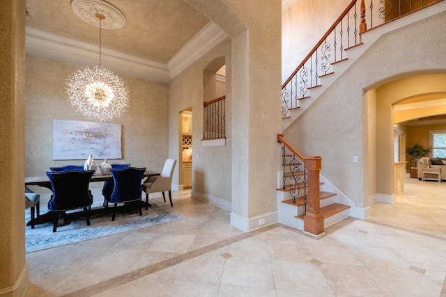 dining room featuring arched walkways, baseboards, ornamental molding, a tray ceiling, and an inviting chandelier