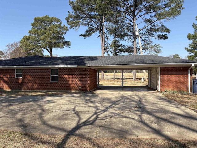 view of side of home featuring driveway, an attached carport, and brick siding