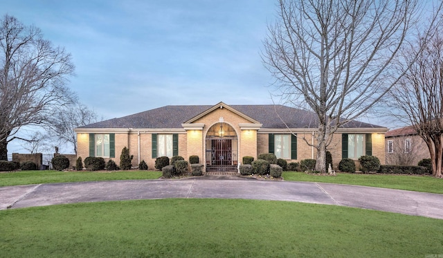 single story home with roof with shingles, brick siding, a front lawn, and driveway