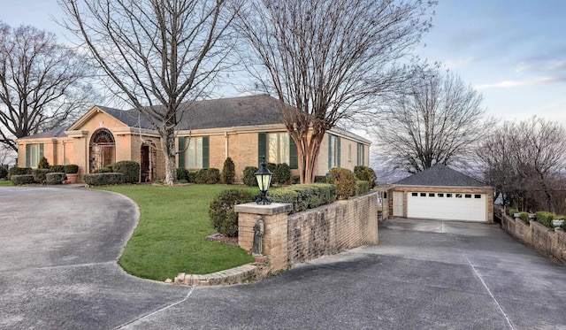 ranch-style house featuring a garage, brick siding, an outdoor structure, fence, and a front lawn