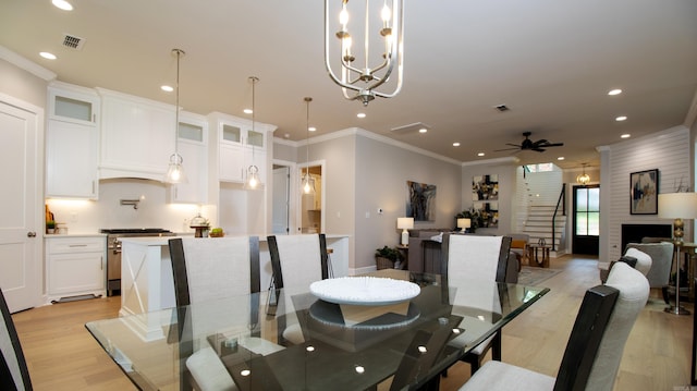 dining space with a ceiling fan, visible vents, light wood-style floors, stairway, and crown molding