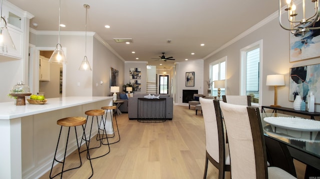 dining area featuring light wood-style floors, a fireplace, crown molding, and recessed lighting