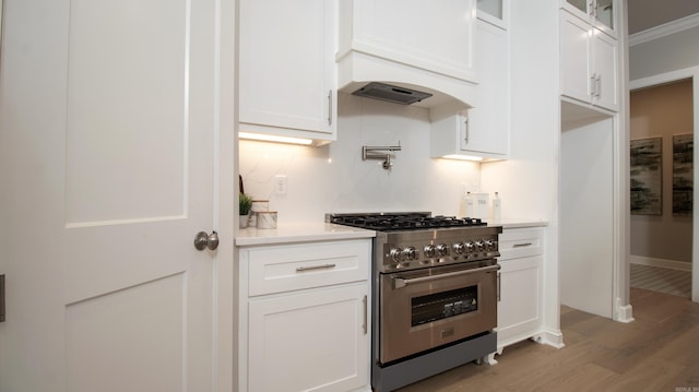 kitchen with glass insert cabinets, light countertops, high end stove, and white cabinetry