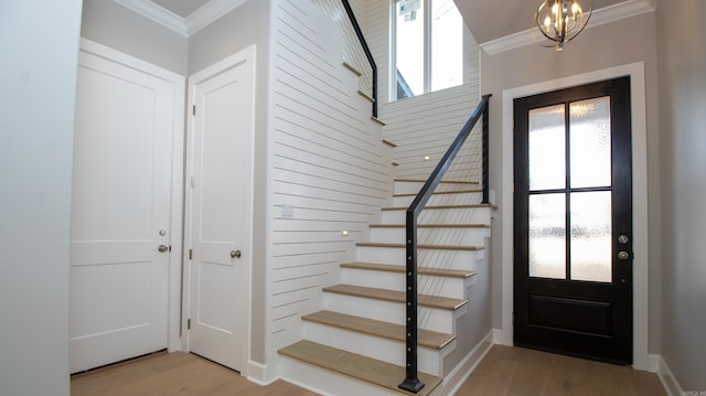 foyer entrance featuring plenty of natural light, crown molding, stairway, and light wood finished floors