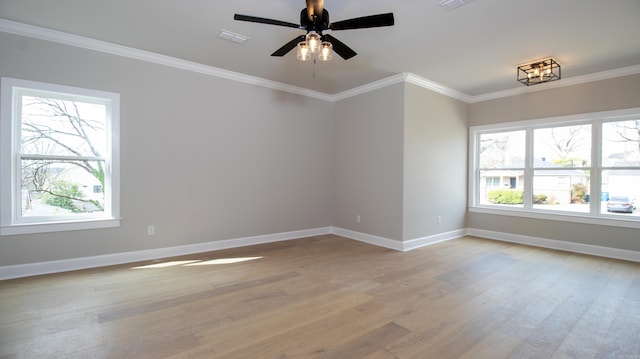 empty room featuring light wood-type flooring, plenty of natural light, and crown molding