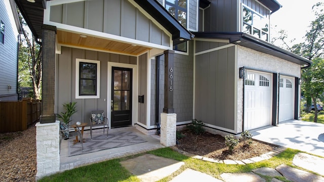 doorway to property featuring board and batten siding, fence, and a garage