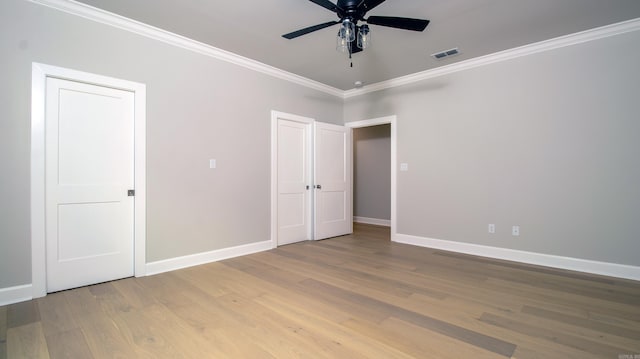 unfurnished bedroom featuring baseboards, visible vents, a ceiling fan, ornamental molding, and wood finished floors