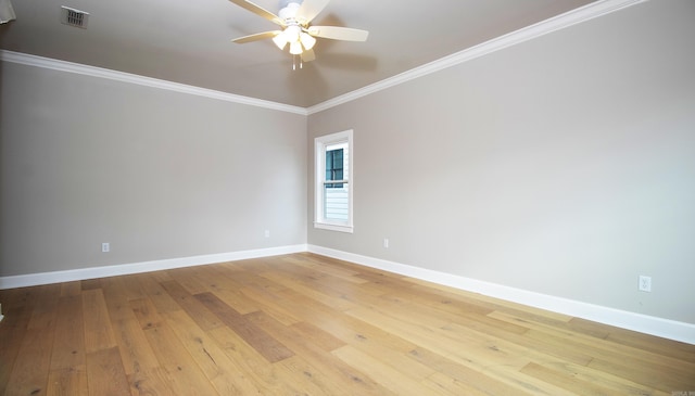 empty room featuring light wood finished floors, baseboards, visible vents, and crown molding