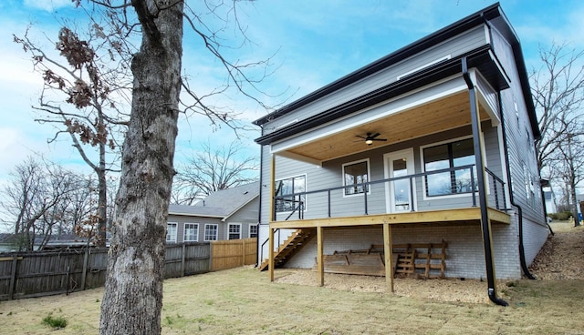 rear view of property featuring brick siding, a yard, fence, ceiling fan, and stairs