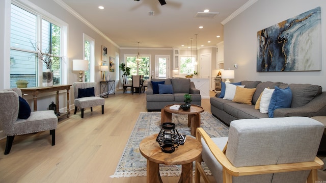 living room with ornamental molding, recessed lighting, light wood-style flooring, and a healthy amount of sunlight