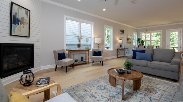 living area with a fireplace, crown molding, baseboards, and wood finished floors