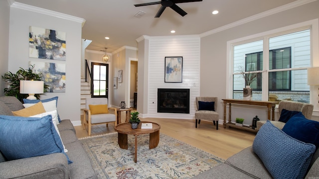 living area featuring baseboards, visible vents, wood finished floors, crown molding, and a fireplace