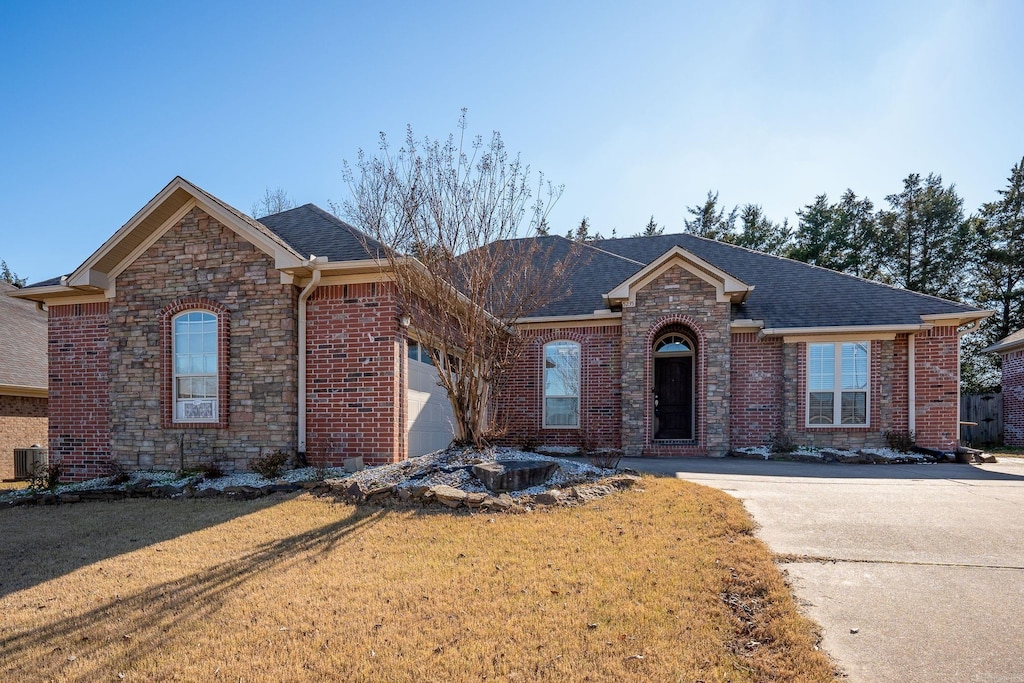 single story home featuring a garage, roof with shingles, a front lawn, and brick siding