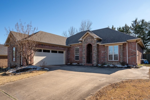 view of front facade with driveway, a shingled roof, a garage, and brick siding