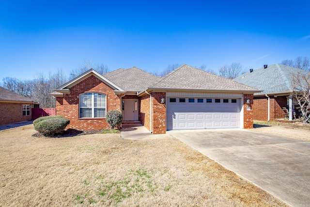 ranch-style home featuring a garage, brick siding, driveway, roof with shingles, and a front lawn