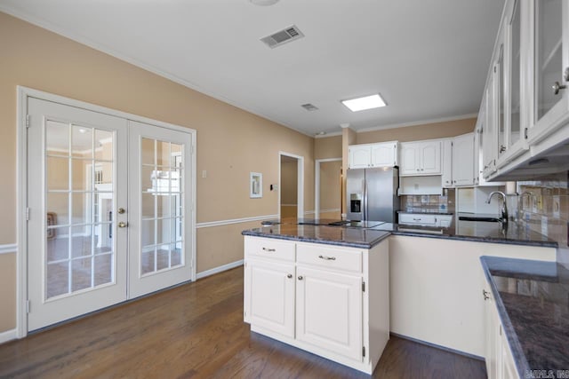 kitchen with a peninsula, a sink, visible vents, white cabinetry, and stainless steel fridge