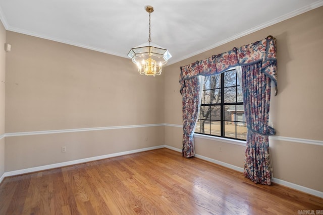 spare room featuring light wood-style floors, baseboards, a notable chandelier, and ornamental molding