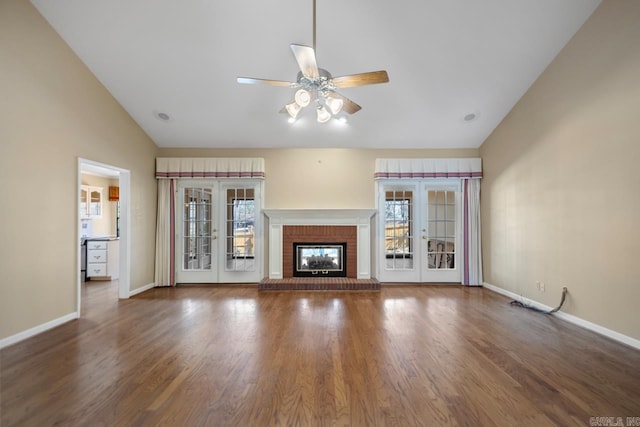 unfurnished living room with lofted ceiling, a brick fireplace, a wealth of natural light, and french doors