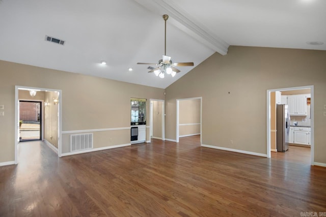 unfurnished living room with a wealth of natural light, visible vents, beamed ceiling, and wood finished floors