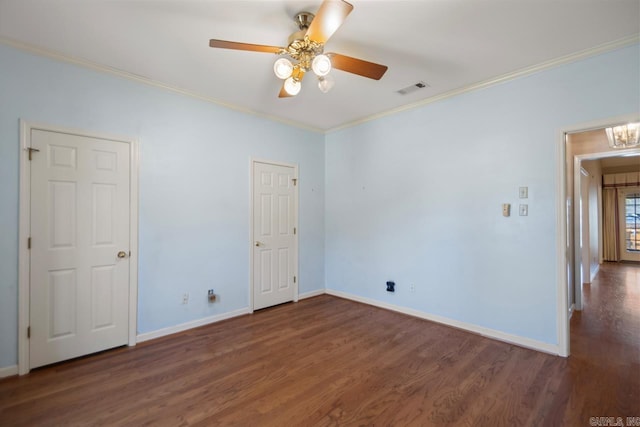 empty room featuring visible vents, crown molding, baseboards, and wood finished floors