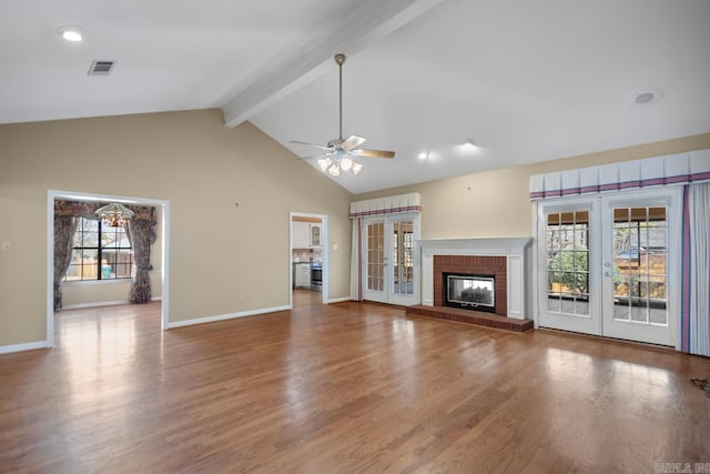 unfurnished living room with visible vents, wood finished floors, french doors, a fireplace, and beam ceiling