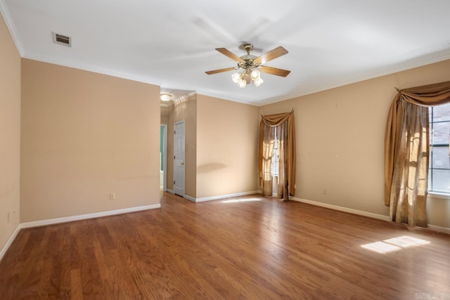 unfurnished room featuring baseboards, wood finished floors, and crown molding