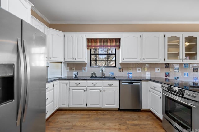 kitchen with crown molding, light wood finished floors, stainless steel appliances, white cabinets, and a sink