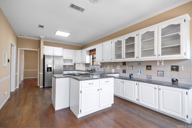 kitchen featuring a center island, visible vents, stainless steel fridge with ice dispenser, decorative backsplash, and dark stone counters