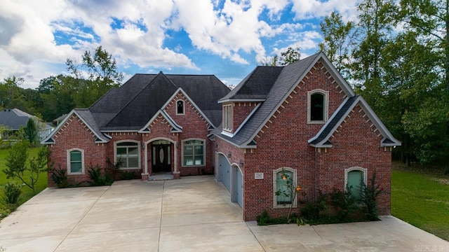 view of front facade with driveway, a front yard, and brick siding