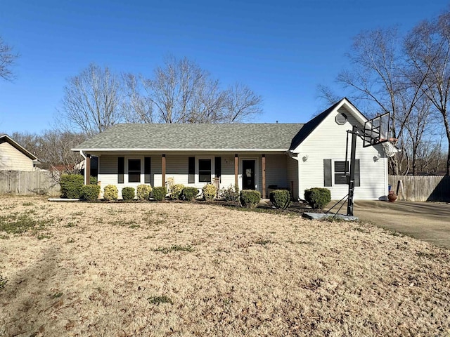 single story home with covered porch, a shingled roof, and fence