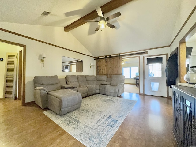 living room featuring lofted ceiling with beams, ceiling fan, wood finished floors, and visible vents