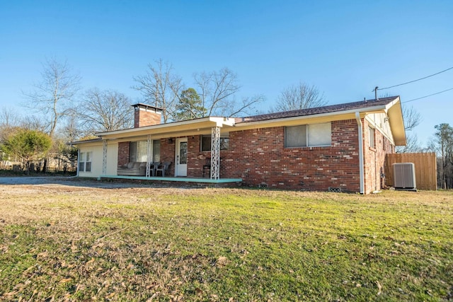 ranch-style home with brick siding, a chimney, central air condition unit, a front yard, and fence