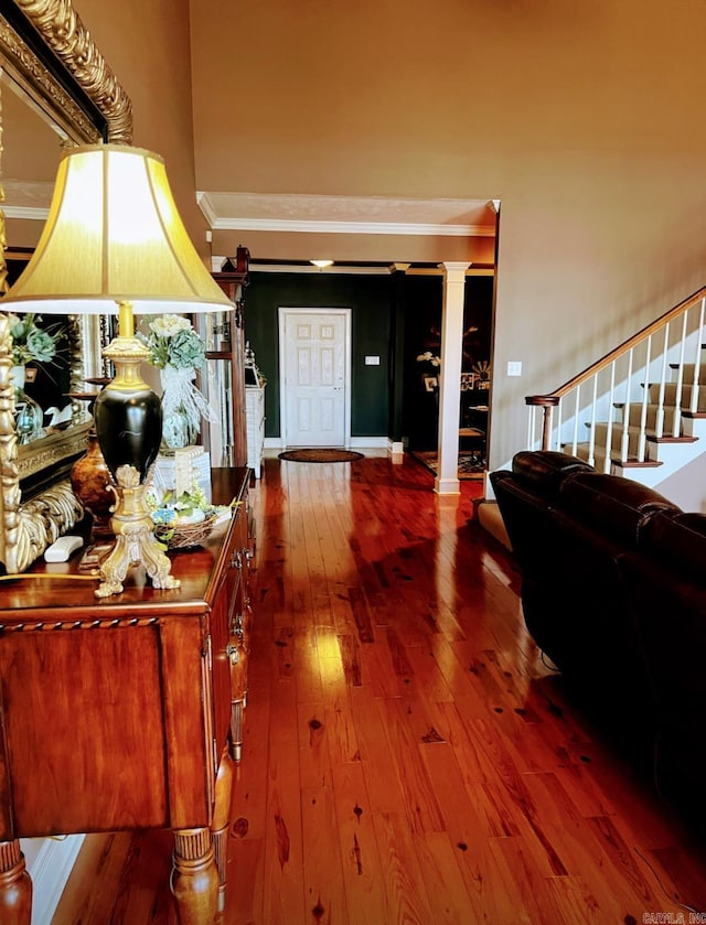 hall featuring stairs, hardwood / wood-style floors, decorative columns, and crown molding