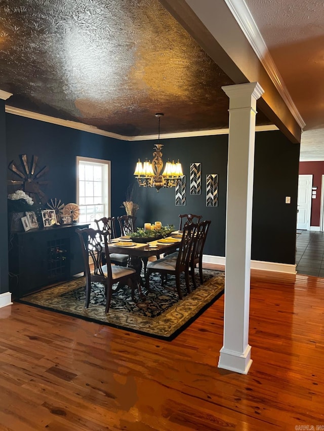 dining area with ornamental molding, a textured ceiling, ornate columns, and wood finished floors