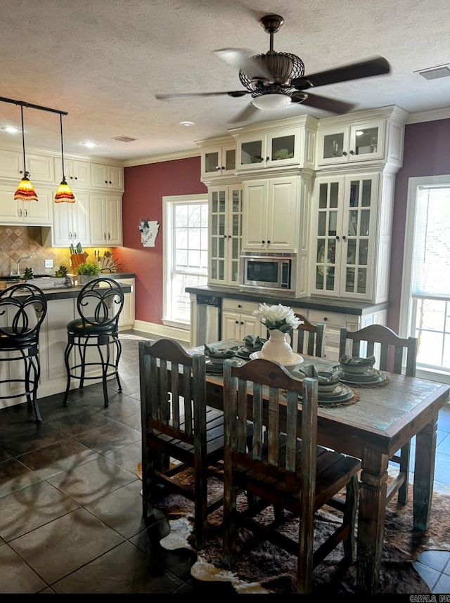 dining area featuring a healthy amount of sunlight, visible vents, and crown molding