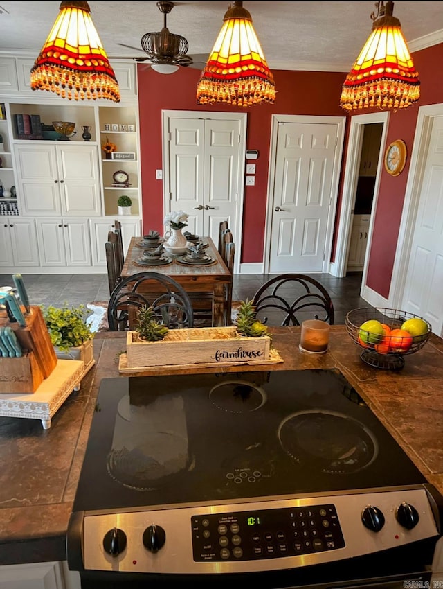 kitchen with electric stove, ornamental molding, decorative light fixtures, and baseboards