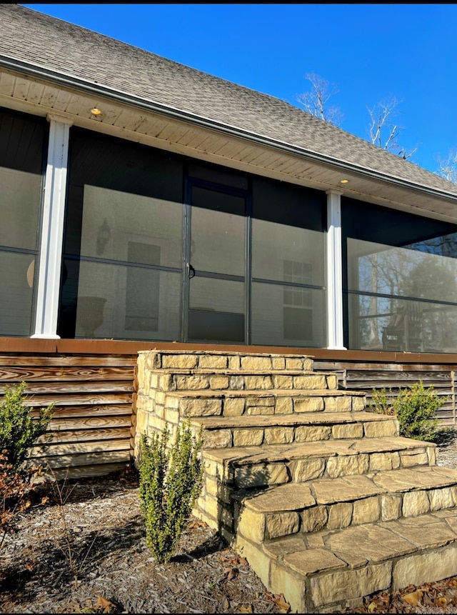 view of side of home featuring a shingled roof and a sunroom