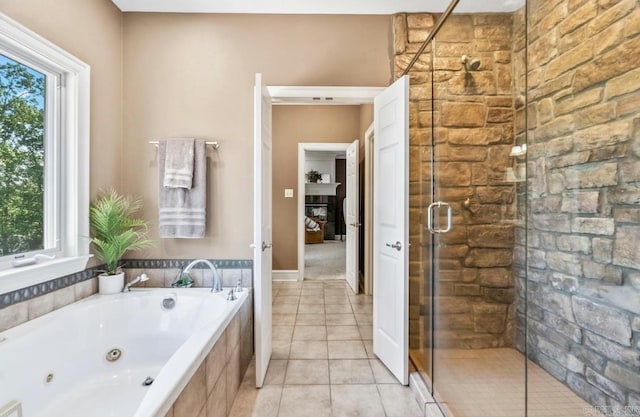 bathroom featuring a whirlpool tub, a stall shower, a fireplace, and tile patterned floors