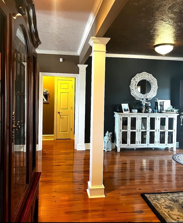 interior space with crown molding, decorative columns, a textured ceiling, and hardwood / wood-style floors