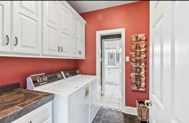 washroom with cabinet space, dark tile patterned floors, baseboards, and washing machine and clothes dryer