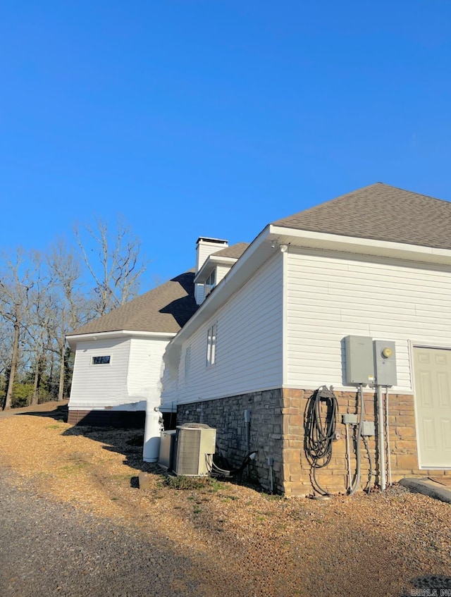 view of property exterior with roof with shingles and central air condition unit