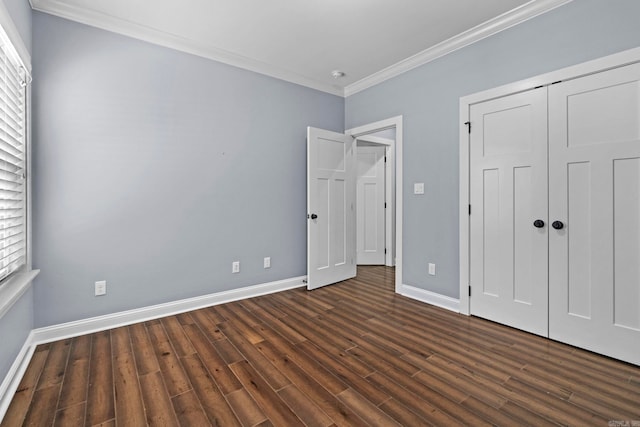 unfurnished bedroom with a closet, baseboards, dark wood-type flooring, and crown molding