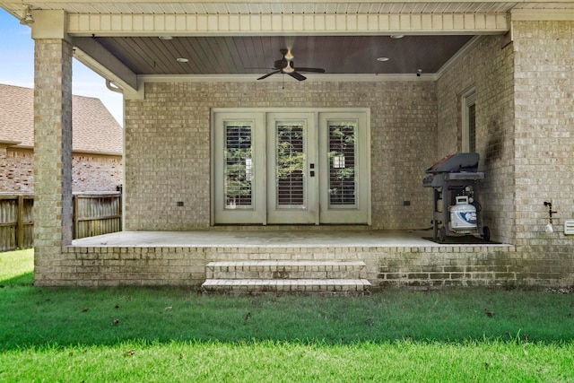 view of exterior entry with a patio, fence, a ceiling fan, and brick siding