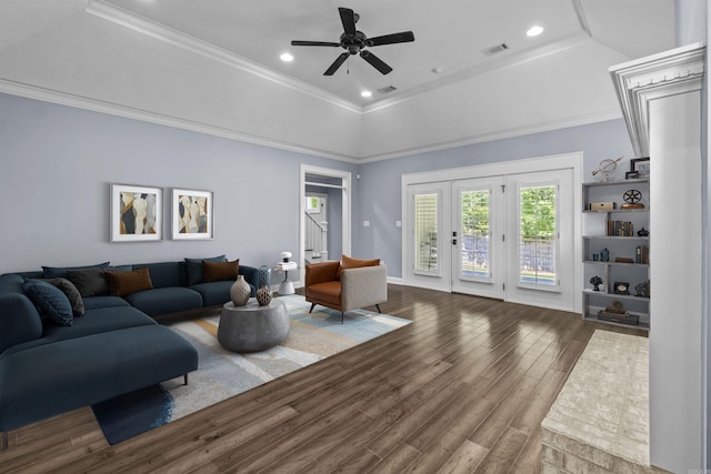 living area with a raised ceiling, crown molding, and wood finished floors