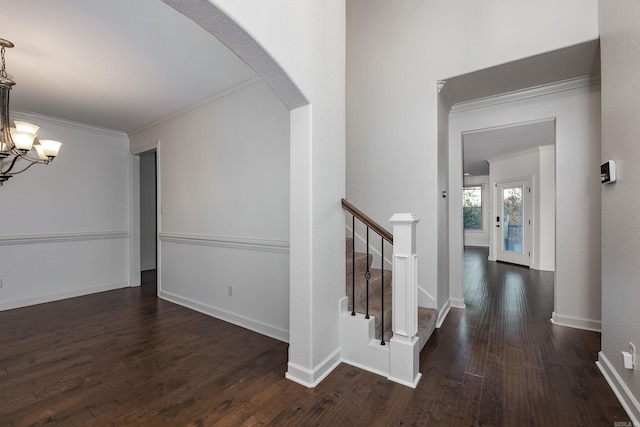 hallway featuring arched walkways, ornamental molding, stairway, wood-type flooring, and an inviting chandelier