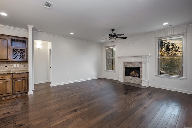 unfurnished living room featuring baseboards, visible vents, a fireplace with flush hearth, dark wood-style flooring, and crown molding